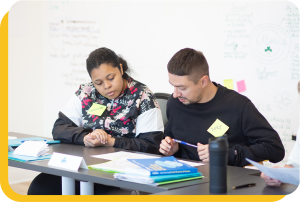 A male and female student working together in a group environment learning soft skills to improve their employability in Quebec.